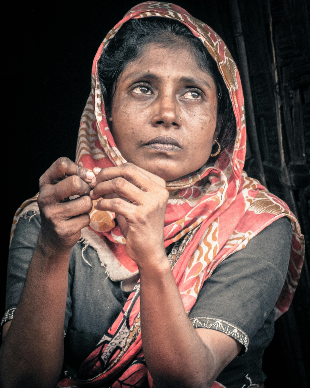 A widowed mother in a patterned shawl, hands clasped — the kind of dignity Mayaar's widow stipend restores