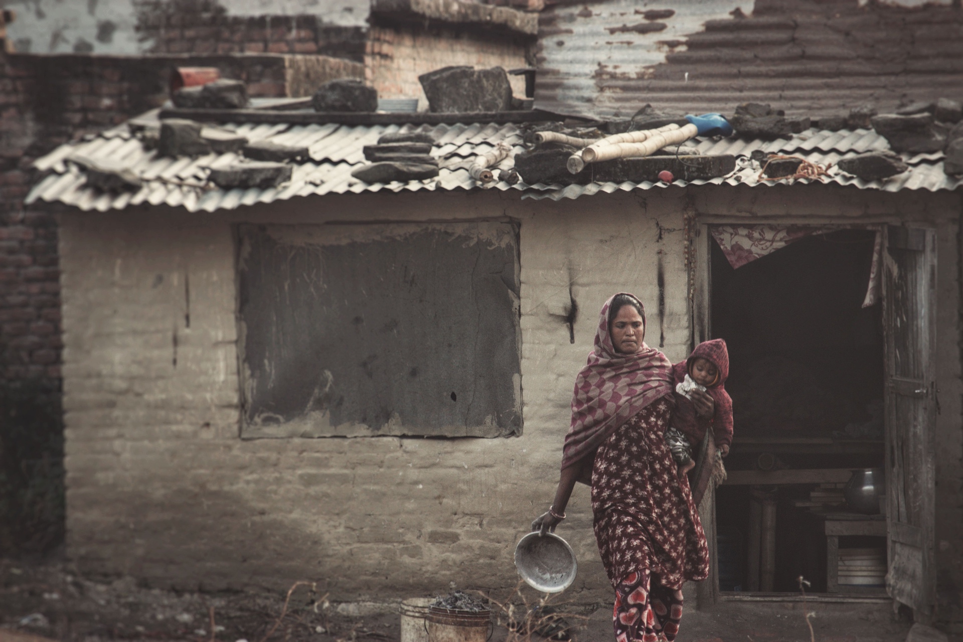 A mother carrying her child outside their home — one of the families your donations support